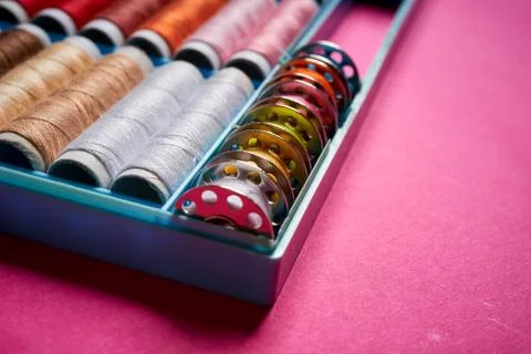 Close up of spools of colored threads in box on pink background Stock Photos