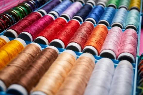 Close up of spools of colored threads in box on pink background Stock Photos