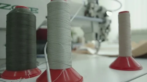 Close-up of spools of thread on blurred background of working sewing machine in 库存影片 150805558