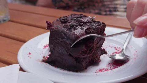 Close-up of spoon cutting into rich chocolate cake in outdoor cafe Stock Footage 321019990