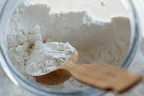 Close-up of a spoon with flour inside a large container Stock-Fotos