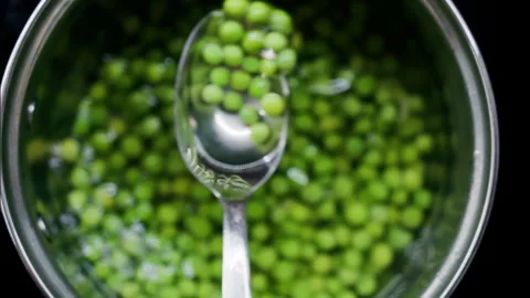 Close up of a spoon picking up green pees with a spoon from a pot with water Stock Footage 311566734