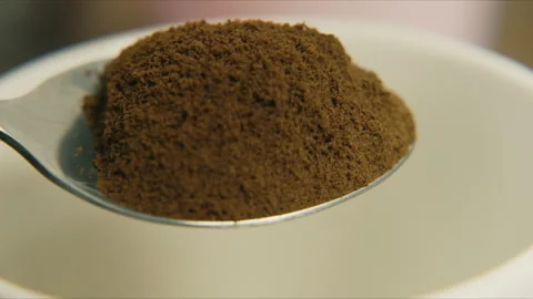 Close up of spoon pouring coffee grind into white bowl for morning beverage Stock Footage 345079861