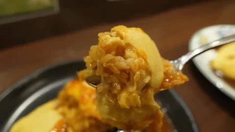 Close-up of Spoon Scooping Delicious Omurice Wrapped in Fluffy Omelet with Rich Stock-Footage 347688331