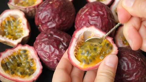 Close up of spoon scooping juicy pulp out of passion fruit shell Stock Footage 344286992