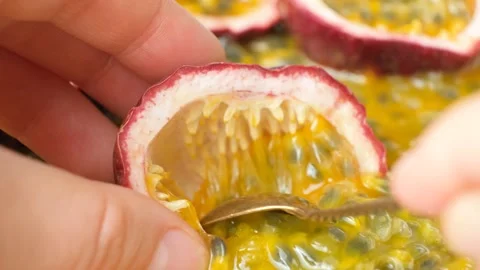 Close up of spoon scooping juicy pulp out of passion fruit shell. Stock Footage 344289400