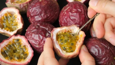 Close up of spoon scooping juicy pulp out of passion fruit shell. Stock Footage 344955374