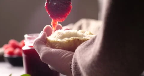 A close-up of a spoon spreading vibrant raspberry or strawberry jam onto 動画素材 297944964