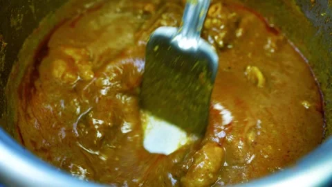 Close-up of spoon stirring thick curry sauce, Close-up view of a metal spoo.. Video stock 346466948