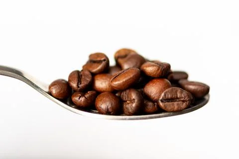 Close-up spoonful of roasted coffee beans isolated on white background Stock Photos
