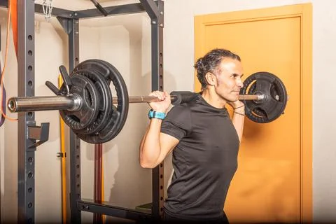Close up of sportsman doing squats with bar at gym Stock Photos