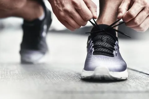 Close-up of sportsman tying sneakers. Unrecognizable man stopping lacing shoe Stock Photos