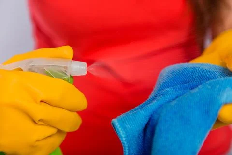 Close-up of spray bottle and rag in the hands of a cleaning lady. Stock Photos