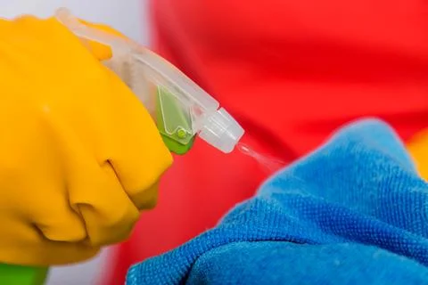 Close-up of spray bottle and rag in the hands of a cleaning lady. Stock Photos