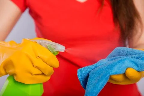 Close-up of spray bottle and rag in the hands of a cleaning lady. Stock Photos