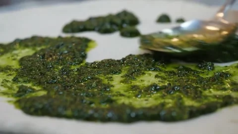 Close-up of Spreading Fresh Green Pesto Sauce on Italian Pizza Dough Base Видео 337678449