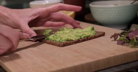 Close up spreading fresh ripe avocado on organic bread, healthy eating concept. Stock Footage 152591600