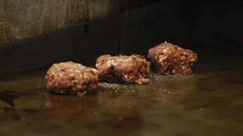 Close up sprinkling salt on half cooked meatballs sizzling on hot plate Stock Footage 91371354