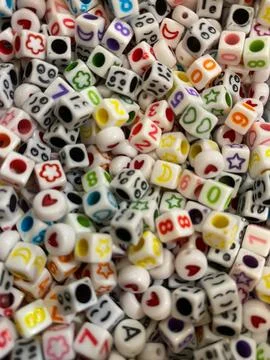 Close up of square beads of various colors and patterns with a hole in the .. Foto stock