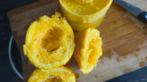 Close up of squeezed orange peels and citrus pulp on a wooden board after jui 库存照片