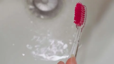 A close-up squeezes the white toothpaste onto the pink head of the toothbrush Stock Footage 202188652