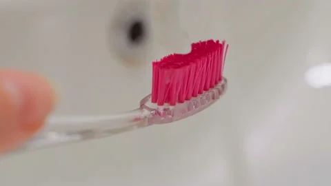 A close-up squeezes the white toothpaste onto the pink head of the toothbrush Stock Footage 202188660