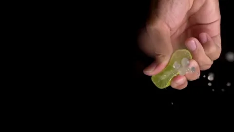 Close-up squeezing fresh lime juice by hand. squeezing juice of half a fresh Vídeo Stock 336588835