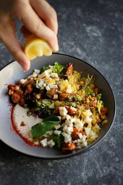 Close up squeezing lemon on salad with dressing Stock Photos