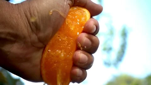 Close-up of squeezing orange juice with splashes by hand, making citrus fru.. Video stock 265841451