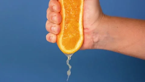 Close-up of squeezing orange juice with splashes by hand, making citrus fruit Stock-Footage 336588931