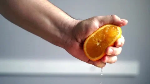 Close-up of squeezing orange juice with splashes by hand, making citrus fruit Stock-Footage 336588960