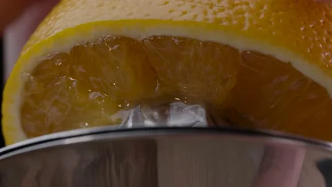 Close-Up Of Squeezing Orange Juice Using A Manual Citrus Juicer. Video stock 143566710