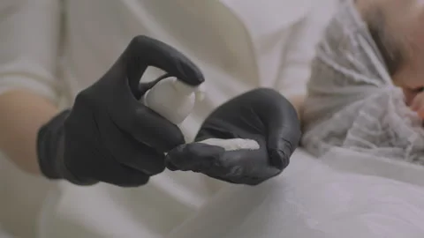 Close-up squeezing out a cream or ointment. A cosmetologist black latex gloves Stock Footage 252609249