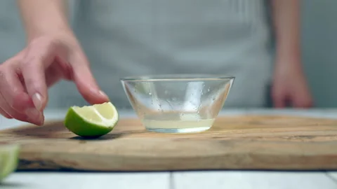 Close-up of squeezing wage lemon in a small glass bowl. Video stock 132789266