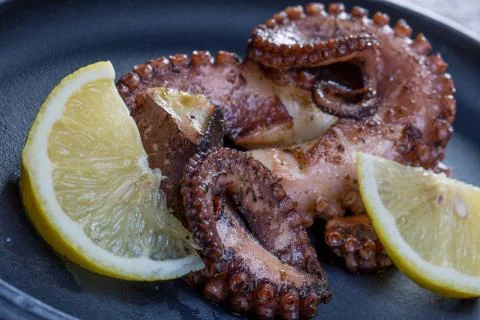 Close up squid tentacles with lemon on black plate Stockfoto's