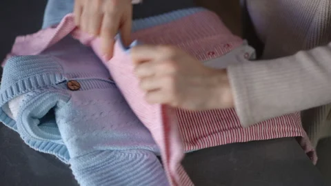 Close-up. A stack of baby clothes lies on a table indoors. An unrecognizable Stock Footage 273168218