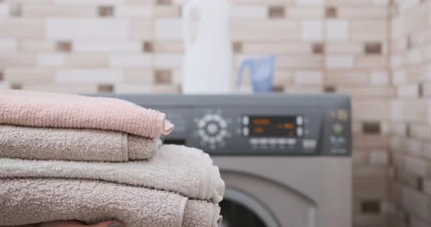 Close-up stack of clean towels in girl hands on washing machine Stock Footage 230094101