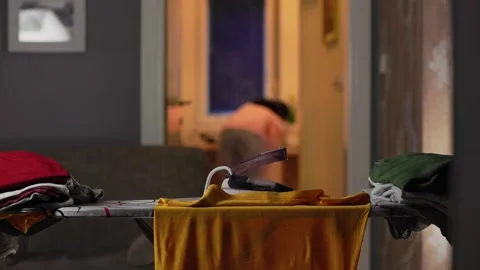 Close up of stack of clothes and steaming hot iron left on ironing board. Stock Footage 234704756