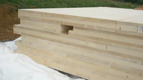 CLOSE UP: A stack of CLT wall panels lie uncovered at a construction site. Stock Footage 152546841