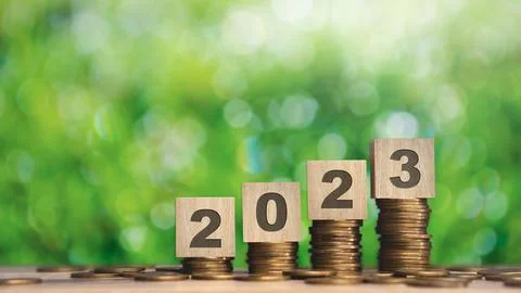 Close up stack of coin and 2023 wooden text block with green backgound on w.. Stock Photos