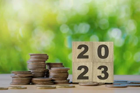 Close up stack of coin and 2023 wooden text block with green backgound on w.. Stock Photos