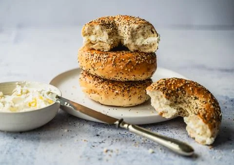 Close up of a stack of everything bagels with cream cheese on a plate. Stock Photos
