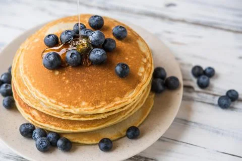 Close up of a stack of fluffy pancakes with maple syrup poured over them. Stock Photos