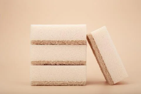 Close up of stack of four beige cleaning or kitchen sponges on bright beige Stock Photos