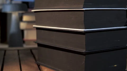 Close-up stack of hardcover volumes on wooden study table Vidéo 334776376