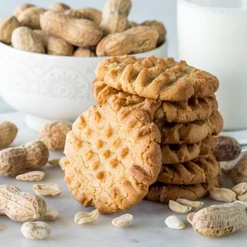 A close up of a stack of homemade peanut butter cookies with a bowl of peanuts. Stock Photos