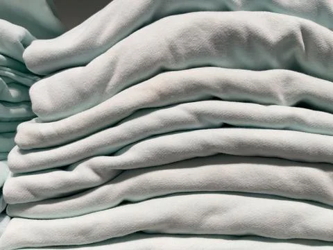 Close-up of a stack of light-coloured clothes on a shelf. Stock Photos