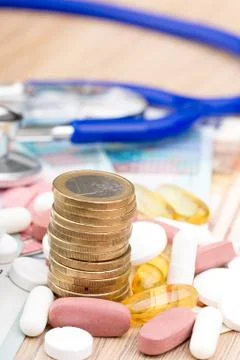 Close up of a stack of money with capsules and a stethoscope in the backgroun Foto stock