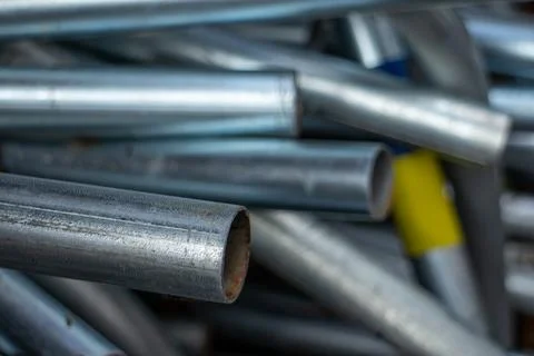 Close-up of a stack of new and used galvanized steel pipes in a workshop 库存照片