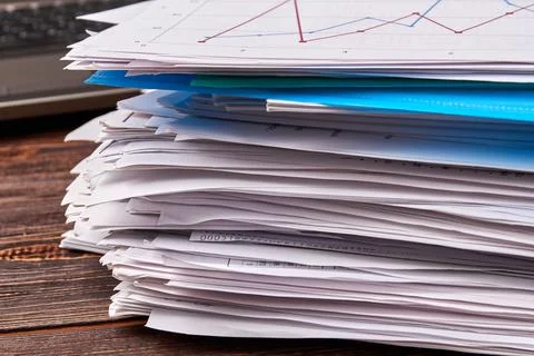 Close-up stack of office work papers on wooden desk. Stock Photos